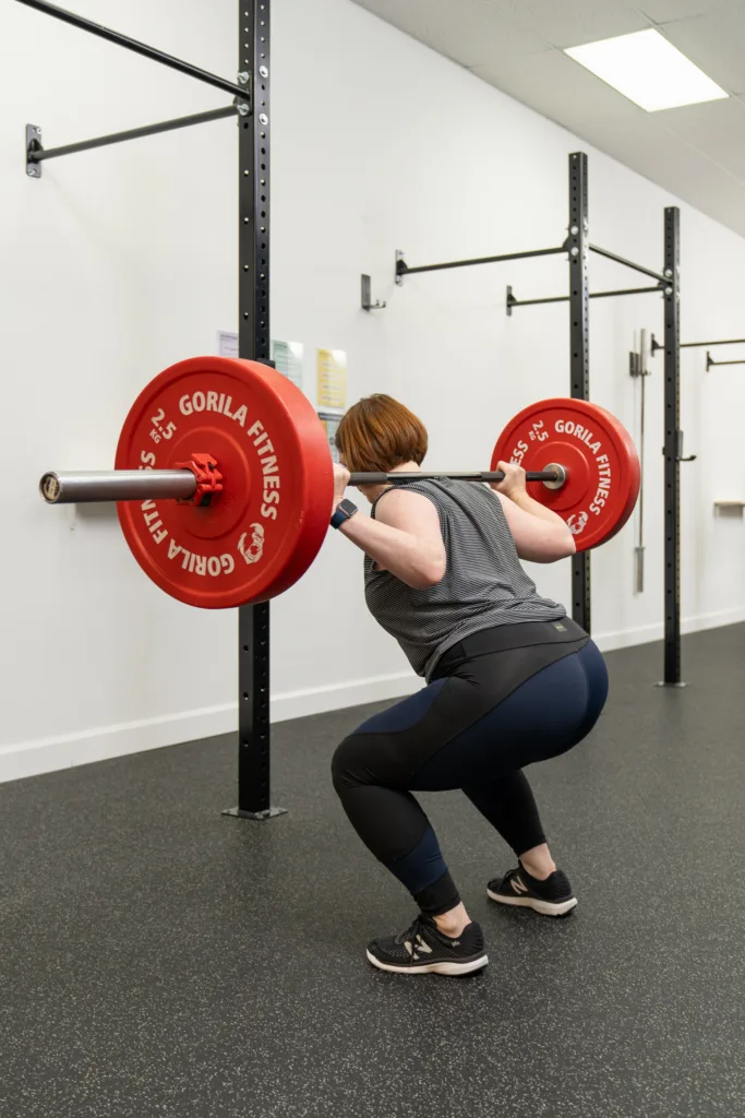 Woman doing a barbell squat in a bright gym