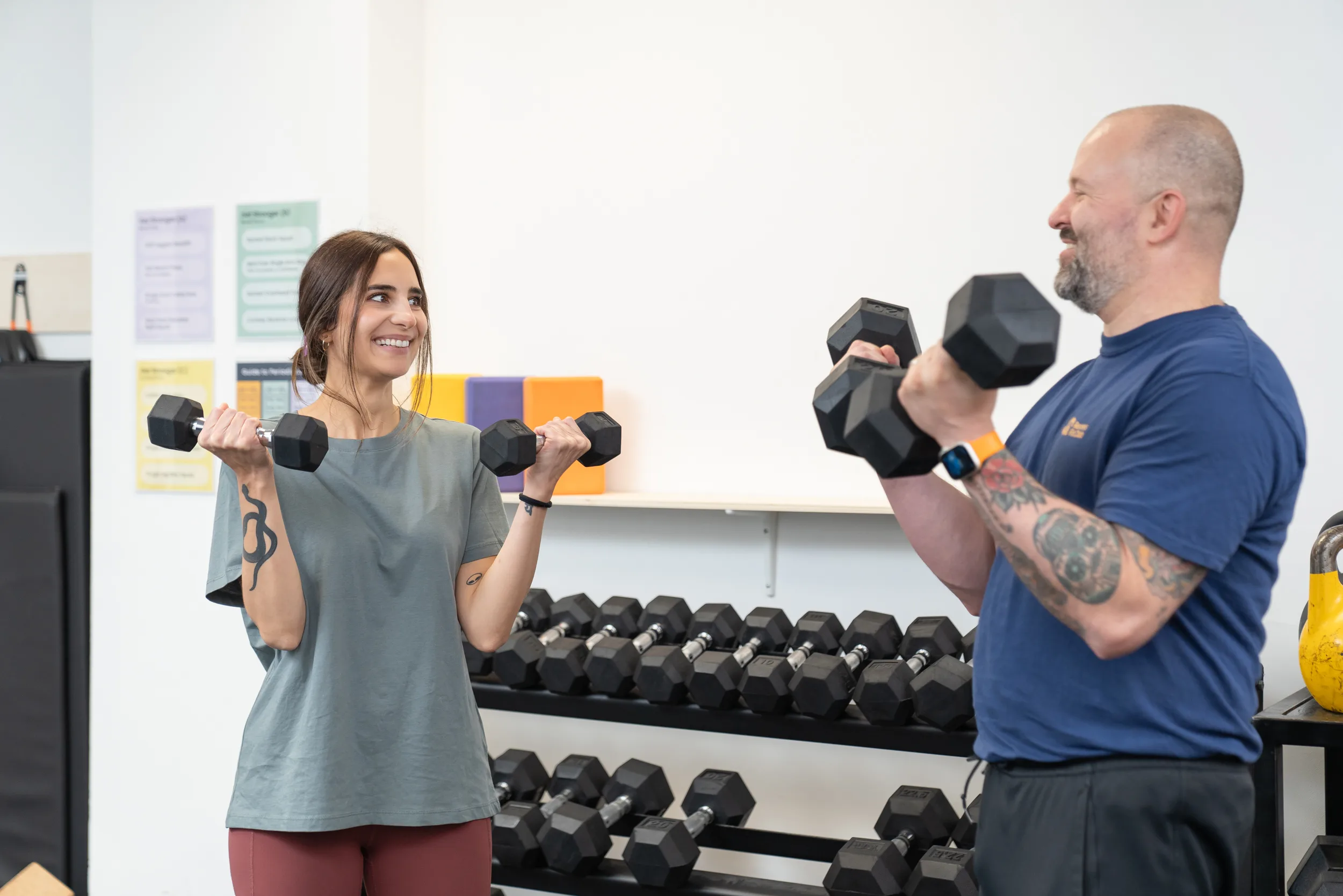 Woman using dumbbells and smiling with a group fitness instructor