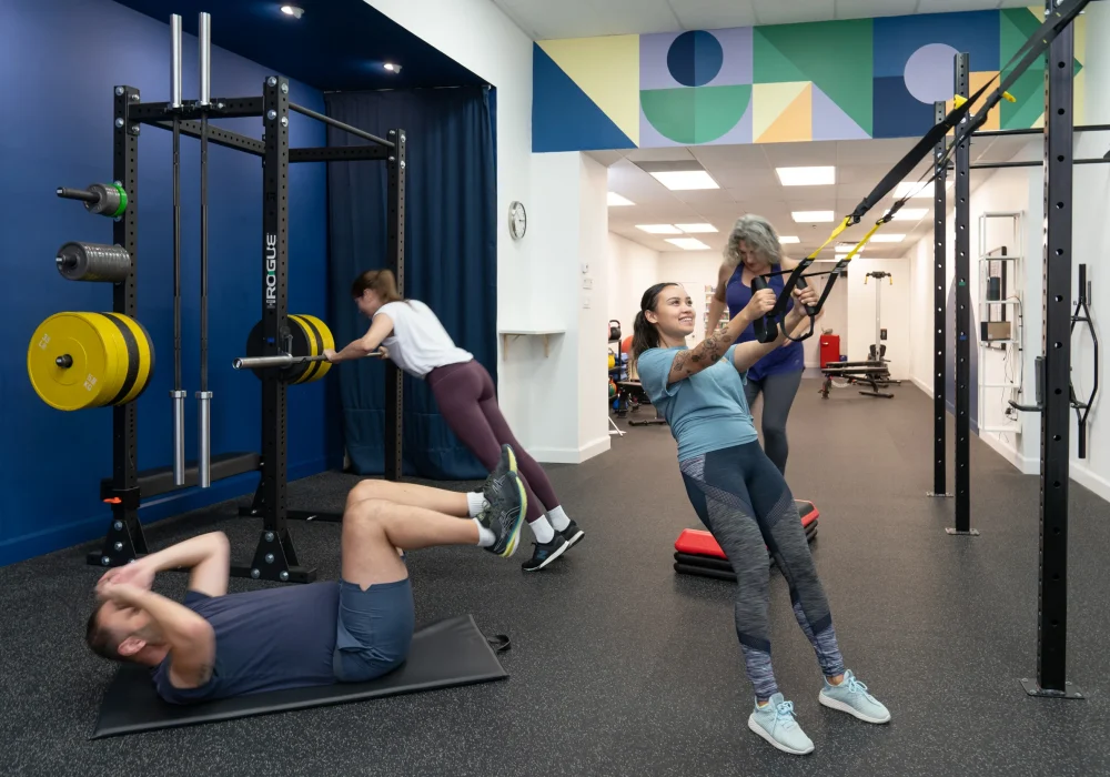 Group fitness class doing different exercises in a bright and colourful gym.